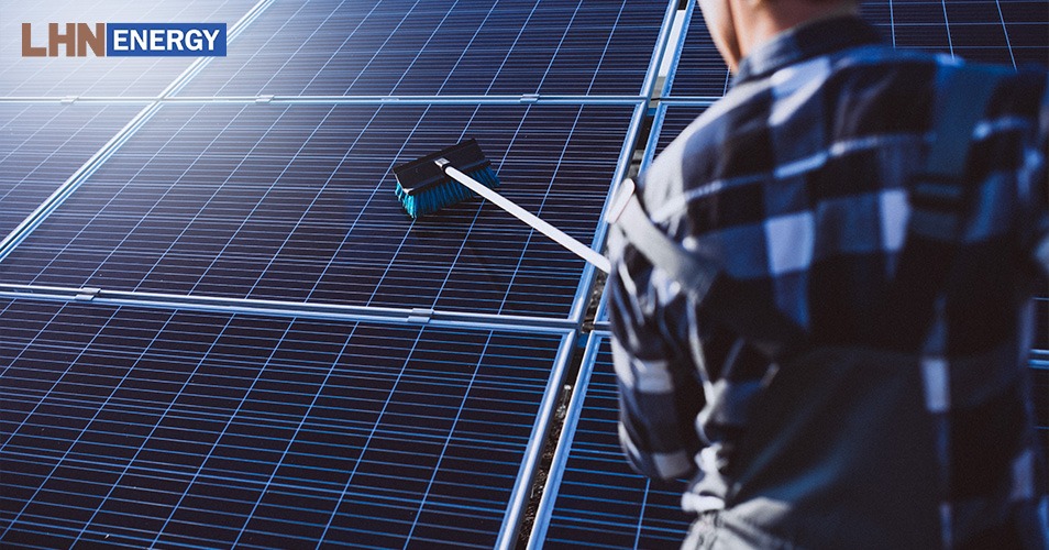 Worker using a brush for professional solar panel cleaning.