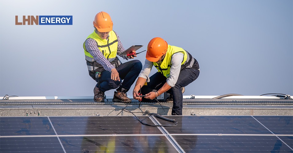 Rooftop solar panels on a residential building and technicians in safety gear performing maintenance on an array.